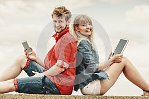 Woman with smartphone man with tablet couple outdoor