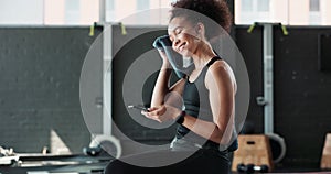 Woman, smartphone and relax in gym or fitness with towel, sweating or exercise break with happiness. Athlete, person and