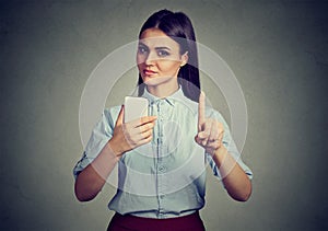 Woman with smartphone showing no, don`t, with finger gesture. Parental control concept