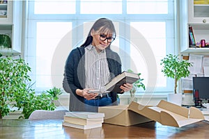 Woman with smartphone unpacking box with books, online shopping