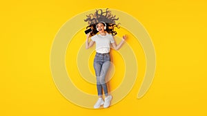 Woman With Smartphone Wearing Earphones Listening Music Over Yellow Background