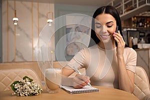 Woman with smartphone working at cafe