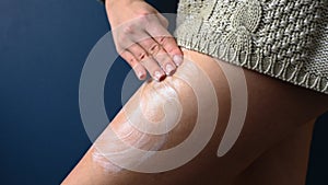 Woman smears cream on her leg with her hands, close-up