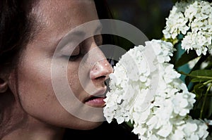 Woman smelling beautiful hydrangea bouquet. Countryside lifestyle gardening. Fashionable girl with flowers. perfect skin. organic