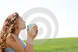 Woman smelling coffee in a field