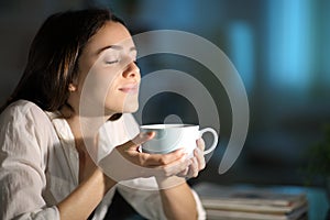 Woman smelling decaffeinated coffee in the night photo