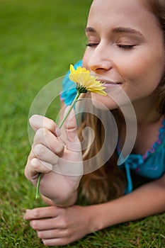 Woman smelling a flower while lying on the grass