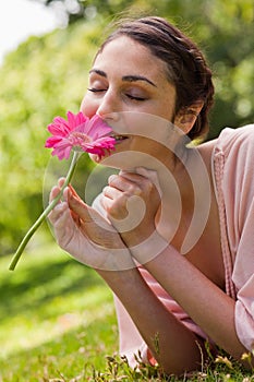 Woman smelling a flower while lying on her front