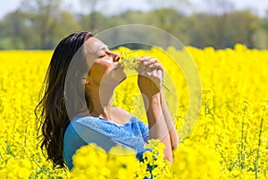 Woman smelling flowers in yellow rapeseed field