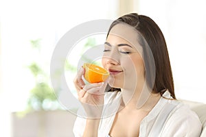 Woman smelling half orange at home