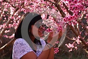 Woman smells the pretty pink peach blossoms