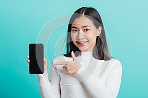 Woman smile holding a smartphone on hand and pointing finger to the blank screen