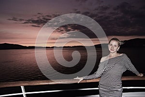 Woman smile on ship deck on dramatic sky over sea in Bergen, Norway. Happy woman enjoy sea travel in evening. Sunset or