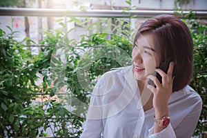 Woman smile and using smart phone , and she looking at view nature park