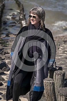 Woman smiles while braving the cold day on the coast
