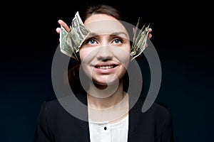 Woman smiles coldly and looks into the dark. Her ears are covered with money photo