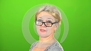 Woman smiles and drops her glasses at the eyes. Green screen