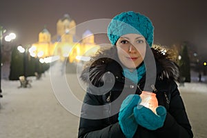 Woman smiles and holds burning candle in glass photo