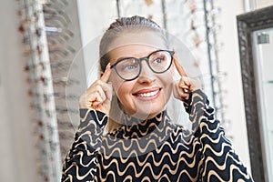 Woman smiling while adjusting glasses on her face