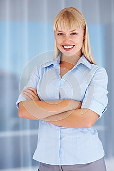 Woman smiling with arms crossed. Portrait of young business woman smiling with hands folded.