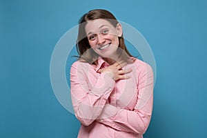 Woman smiling broadly and keeping hand on her chest, glad to receive compliments