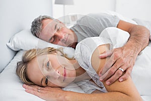 Woman smiling at camera as husband is sleeping