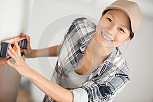 Woman smiling at camera while holding sprit level