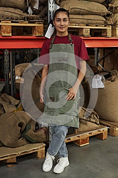 Woman Smiling at Camera and Wearing Apron Standing in Coffee Shop Warehouse