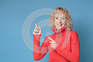 Woman smiling cheerfully and pointing with forefingers aside