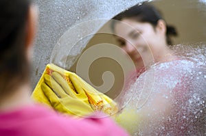 Woman smiling cleaning a mirror