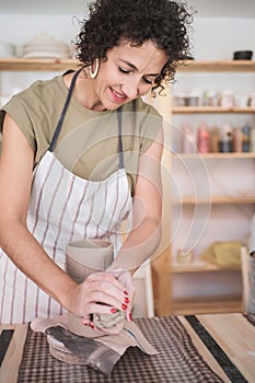 Woman smiling while enjoying creating a handmade ceramic piece in a workshop.