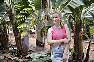 Woman smiling gently and enjoying the nature surrounding her, a banana plantation with lots of healthy trees in Tenerife