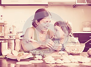 Woman with a smiling girl dumplings fish cooking together at ho