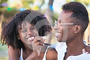 Woman smiling while having fun feeding her boyfriend during a picnic in a park.