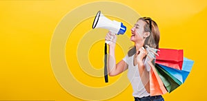 Woman smiling hold shopping bags multi-color and shouting in megaphone