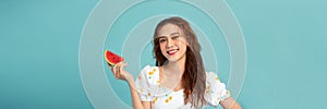 Woman smiling holding and eating slice fresh watermelon on blue background