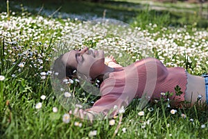 Woman smiling lying on a carpet of daisies in spring