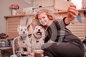Woman smiling while making photo with birthday dogs