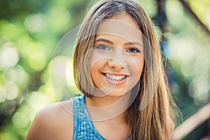 Woman smiling with perfect smile and white teeth in a park and looking at camera