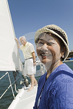 Woman smiling on sailboat husband in background (portrait)