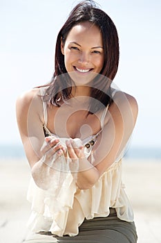 Woman smiling with sand falling through fingers