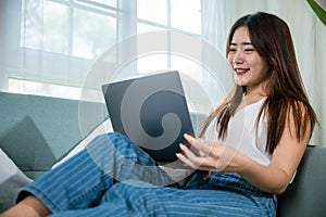 woman smiling sitting relaxing on sofa using laptop in living room at home