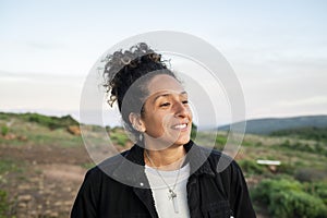 Woman smiling while standing outdoors in nature.