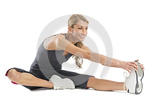 Woman Smiling While Stretching To Touch Her Toes