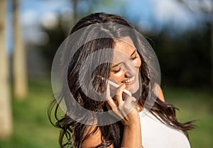 Woman smiling while talking on the phone standing outdoors in nature