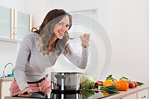 Woman Smiling While Tasting Meal In Kitchen