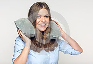 Woman smiling with teeth holding travel pillow on neck.