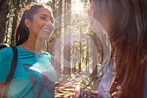 Woman smiling to friend at hiking trail path in forest woods during sunny day.Group of friends people summer adventure