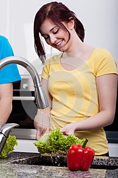 Woman smiling during washing a lettuce