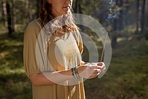 woman with smoking incense stick in forest